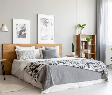 Vitt sovrum med dubbelsäng, trendiga sängbord och gröna växter på vägghylla